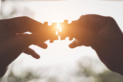 Close-up of hand holding sun against sky during sunset