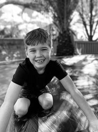 Boy smiling outdoors on the trampoline by the palm trees