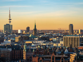 Modern buildings in city against sky during sunset