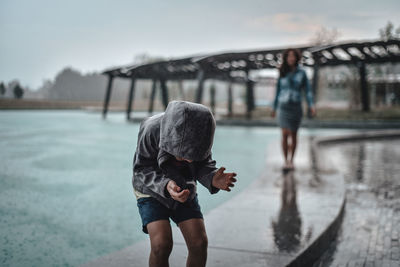 Rear view of boy standing in water during rainy season