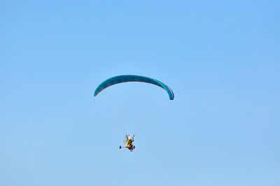 Low angle view of man paragliding against blue sky