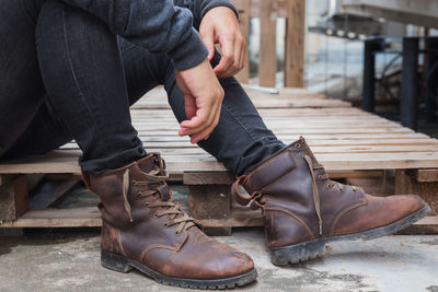 Low section of man wearing shoes while sitting on palette