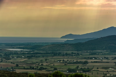 Scenic view of agricultural landscape against sky during sunset