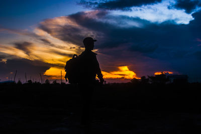 Silhouette man standing on field against sky during sunset