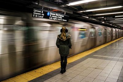 Full length rear view of woman standing at railroad station