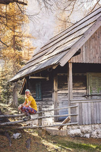 Side view of woman sitting on wooden house