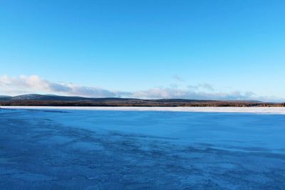 Scenic view of frozen lake against blue sky