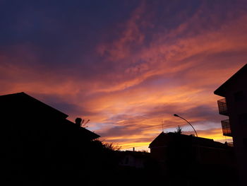 Low angle view of silhouette buildings against orange sky