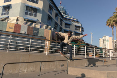 Low angle view of man playing in city against sky