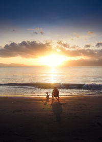 A man and his child sitting at the beach to see beautiful sunrise.