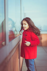 Smiling girl standing against red wall