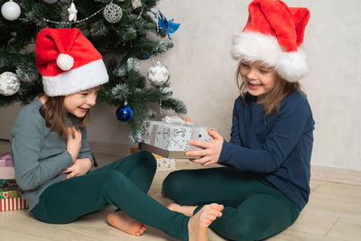 Children give each other a gift at the christmas tree. christmas holiday. real people, simple life