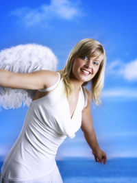 Portrait of smiling young woman against blue sky