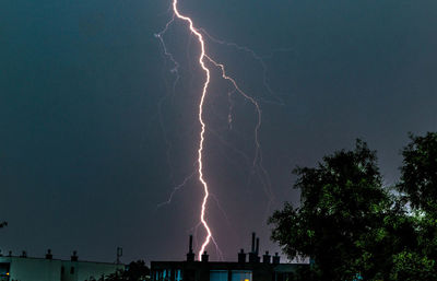 Low angle view of lightning over city at night