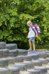 Smiling little girl with school bag on playground