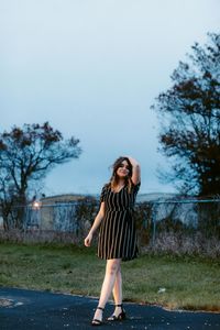 Full length of young woman standing against tree