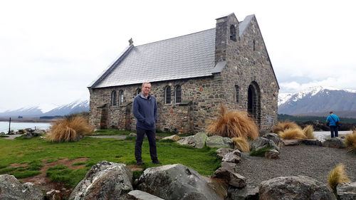 Portrait of man standing on field against church