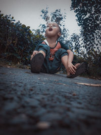 Cute boy looking away while sitting on plant