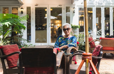 Portrait of senior woman in sunglasses sitting on a chair in cafe outdoor