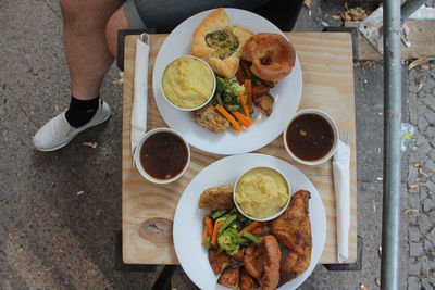 Low section of man standing by food on table at sidewalk cafe