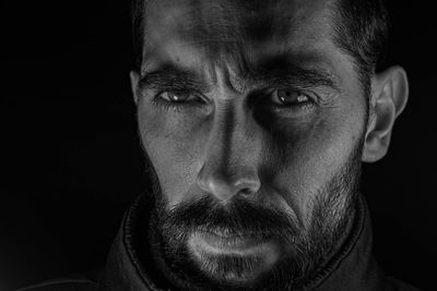 Close-up portrait of mid adult man against black background