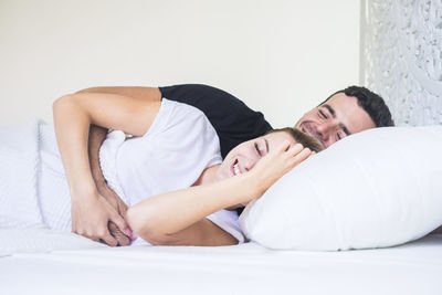 Smiling couple lying on bed at home