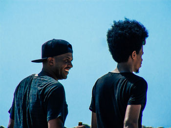 Young man looking away against blue sky
