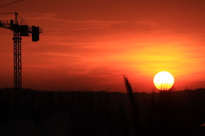 Silhouette electricity pylon on field against romantic sky at sunset