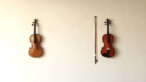 Violins and cello with bow hanging against wall