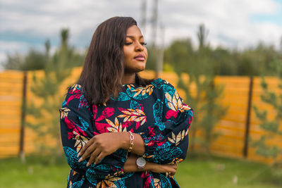 Portrait of young woman standing against trees