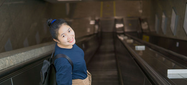 Portrait of young woman walking on escalator