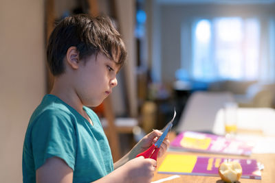 Portrait of boy holding mobile phone at home