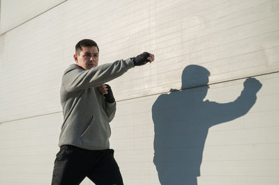 Side view of man standing against wall