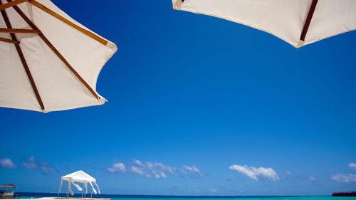 Low angle view of white parasol against blue sky of maldives resort