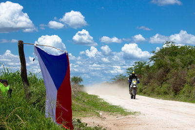 Rear view of man cycling on road against sky