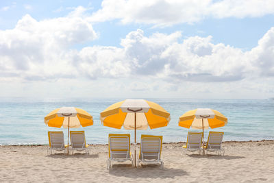 Deck chairs at beach against sky