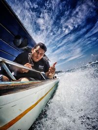 Boy in boat at sea against sky