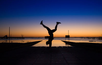 Silhouette man on beach against clear sky during sunset