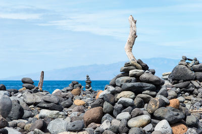 Stack of stones on rocky beach against sky