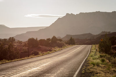 Road leading towards mountains against sky