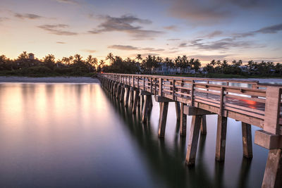 Pier over lake against sky during sunset