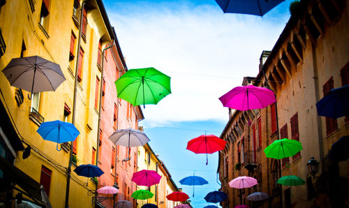 Colorful umbrellas hanging on amidst buildings