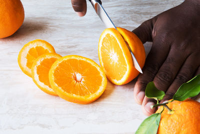 Midsection of man holding orange slices on table