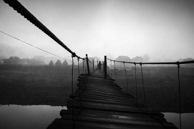 Fence by bridge against sky