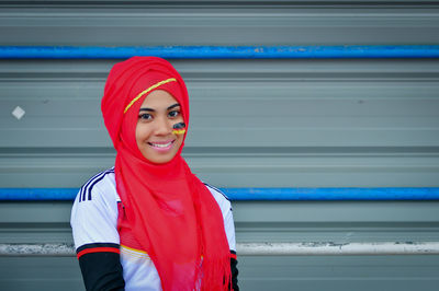 Portrait of young woman standing against wall