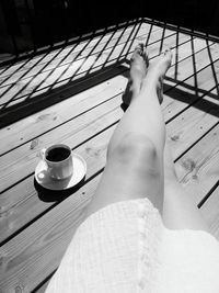 Low section of woman resting on balcony by black coffee