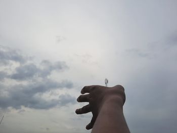 Person holding cigarette against sky