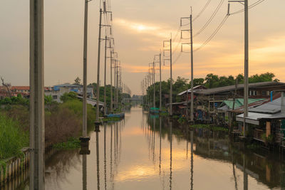 Sailboats moored on canal against sky during sunset