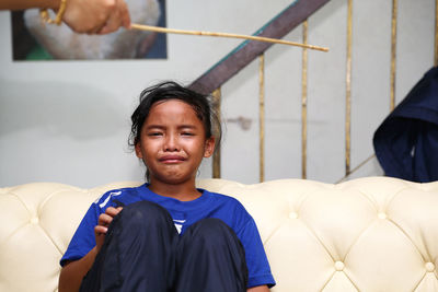 Portrait of crying girl sitting on sofa