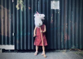 Full length of woman standing against wall